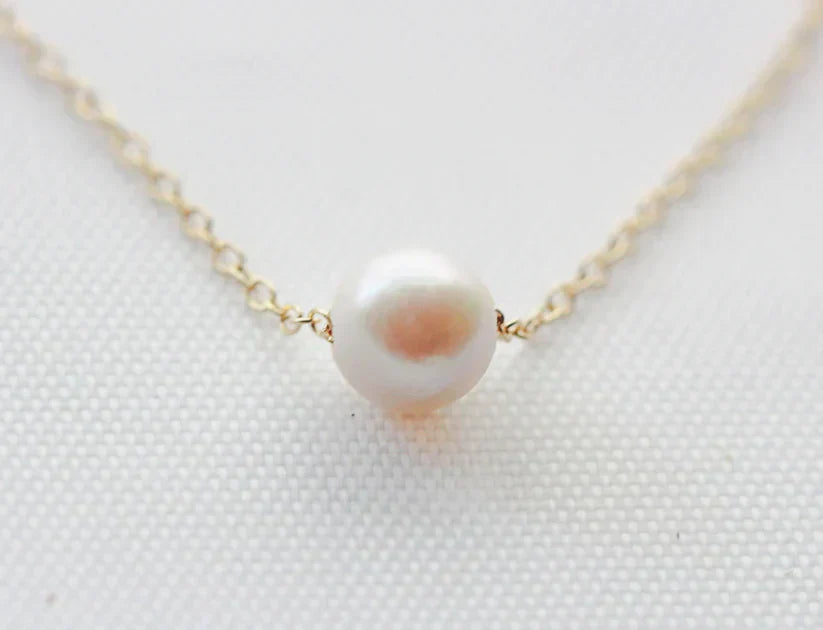 akoya white pearl solitaire necklace on gold chain with white background