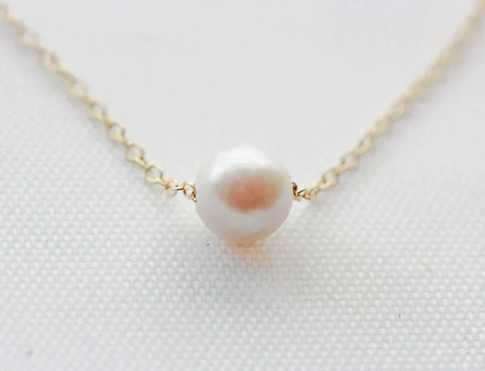 akoya white pearl solitaire necklace on gold chain with white background