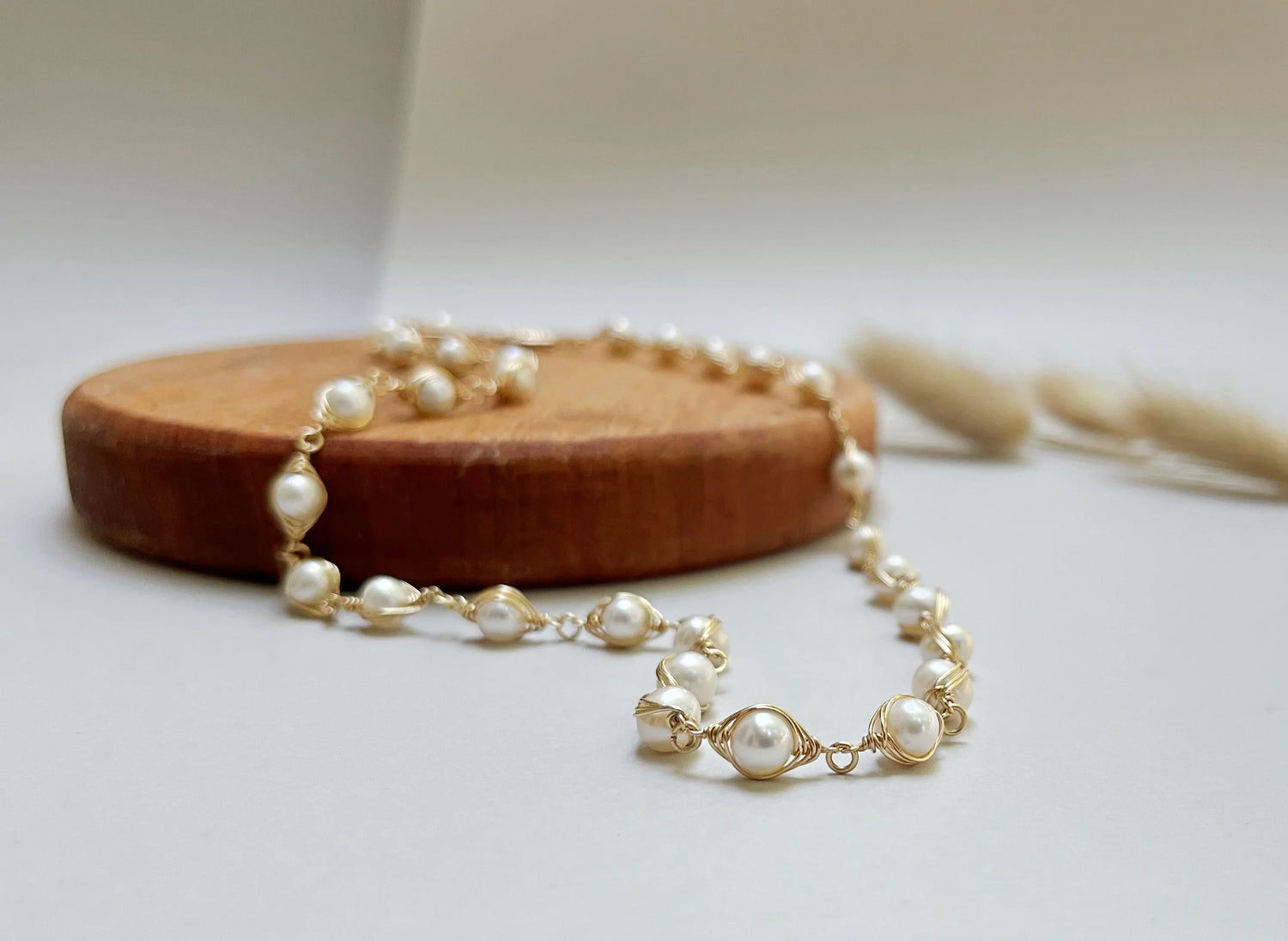 White pearl wedding necklace on a wooden platform and white background.