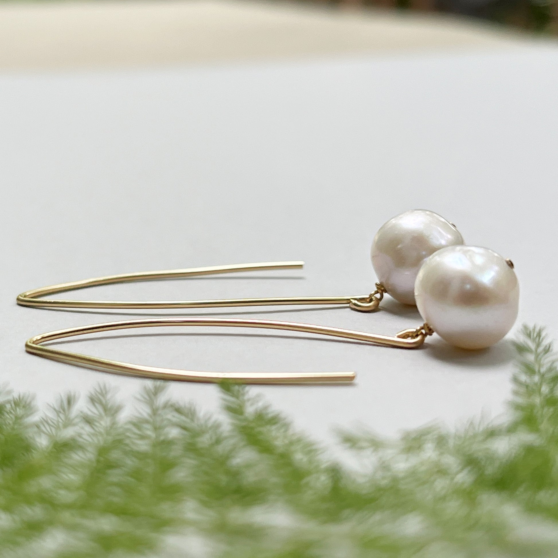 A pair of French Wire Pearl Earrings lying on a table.