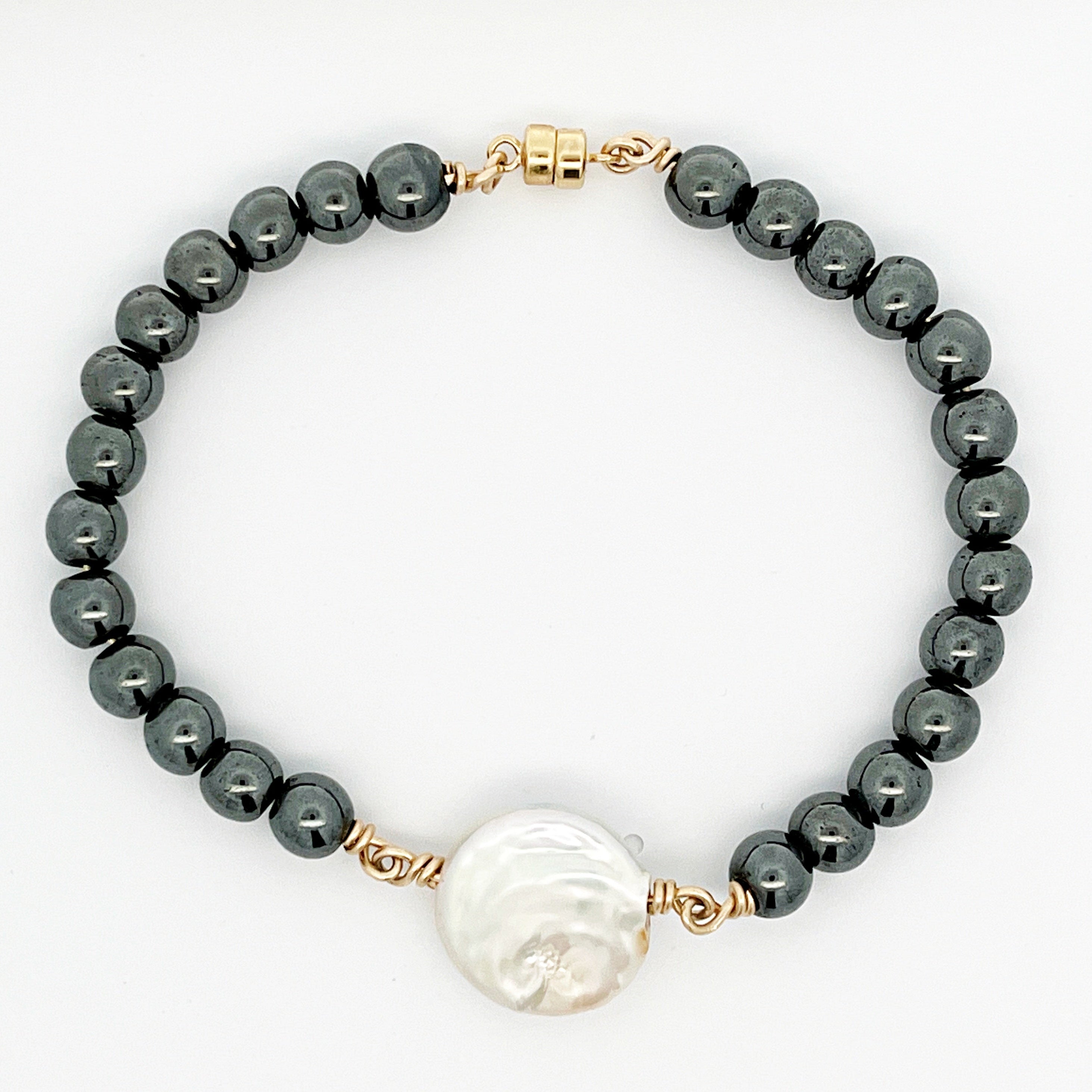 Pearl bracelet with dark beads and a large white bead on a white background