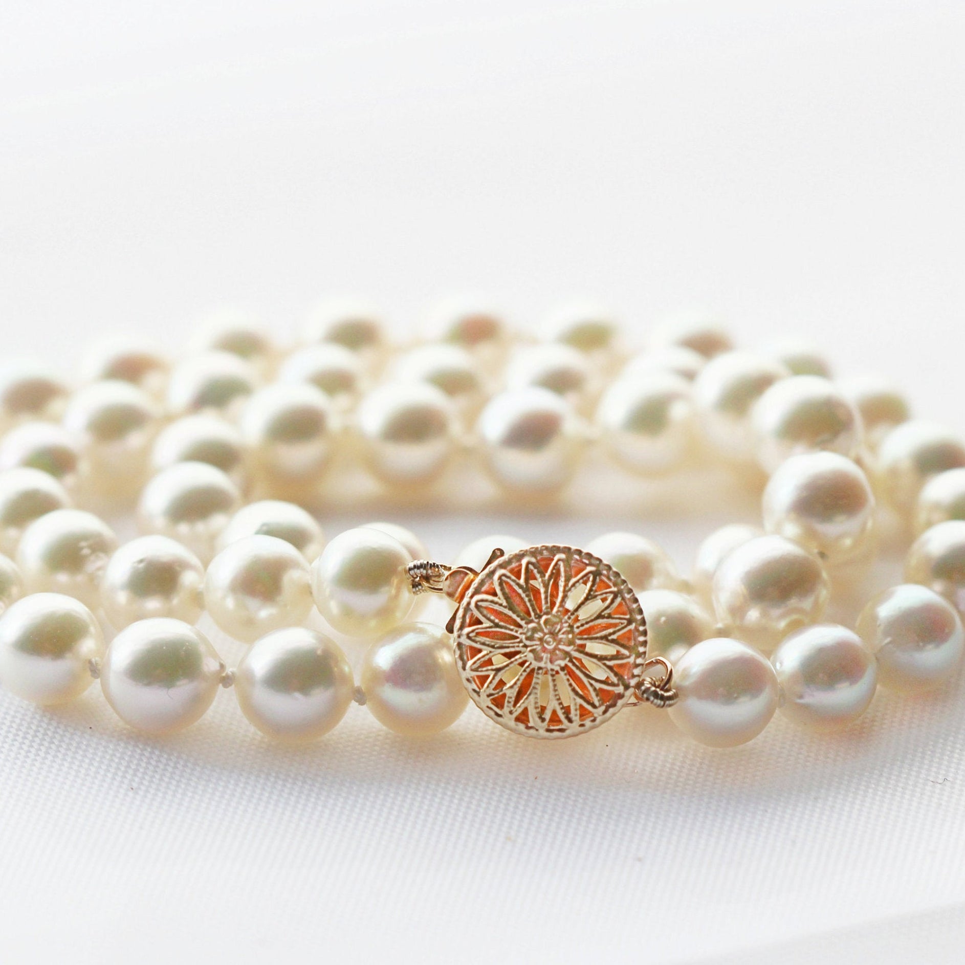 Saltwater pearl necklace on a white linen table.