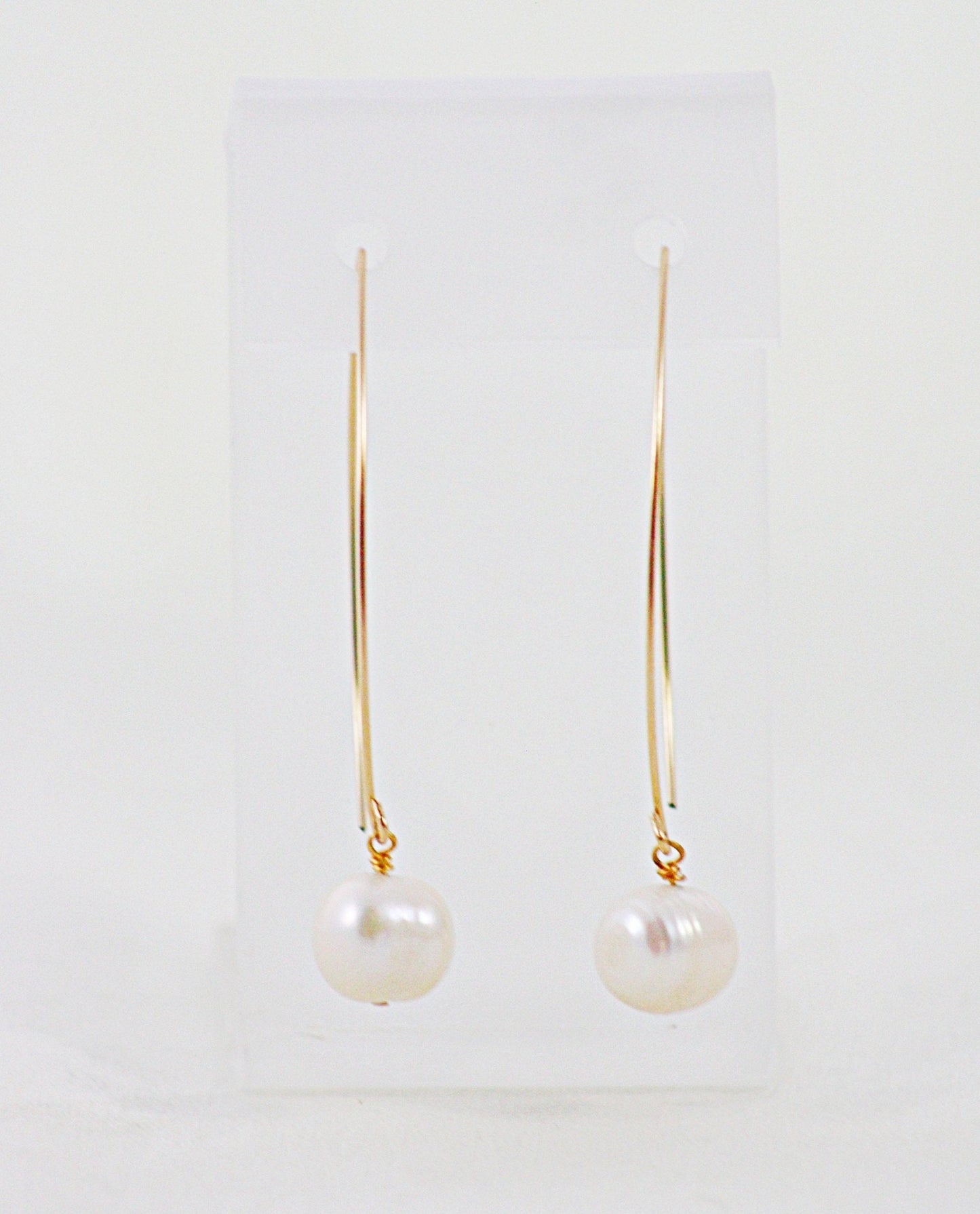 A pair of French Wire Pearl Earrings on a display stand.