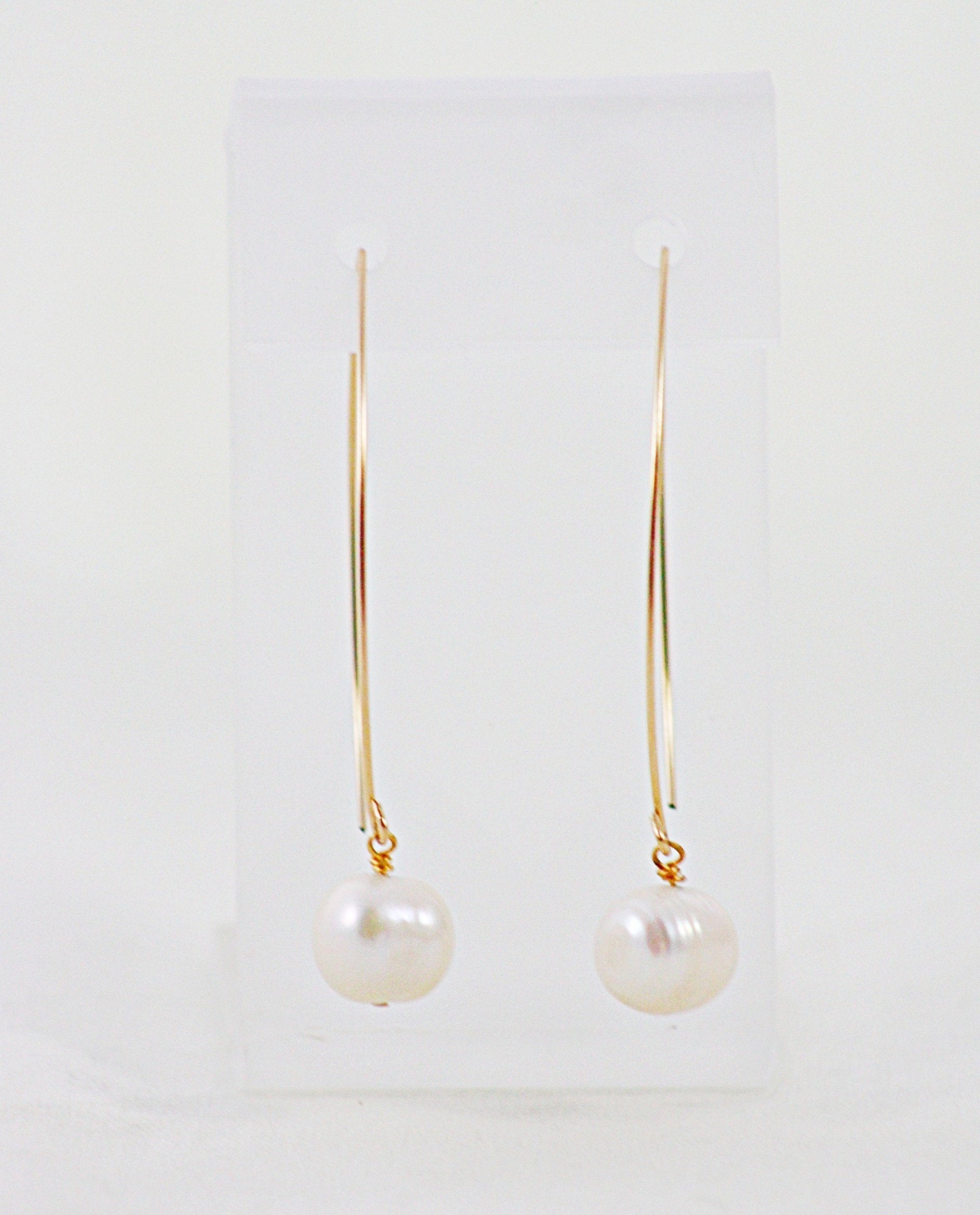 A pair of French Wire Pearl Earrings on a display stand.